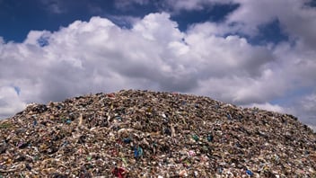 Large landfill waste pile under cloudy sky
