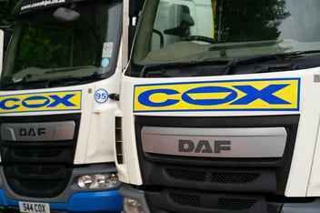 Close-up view of two branded Cox Group skip lorries in CIRQLR's Southern Division