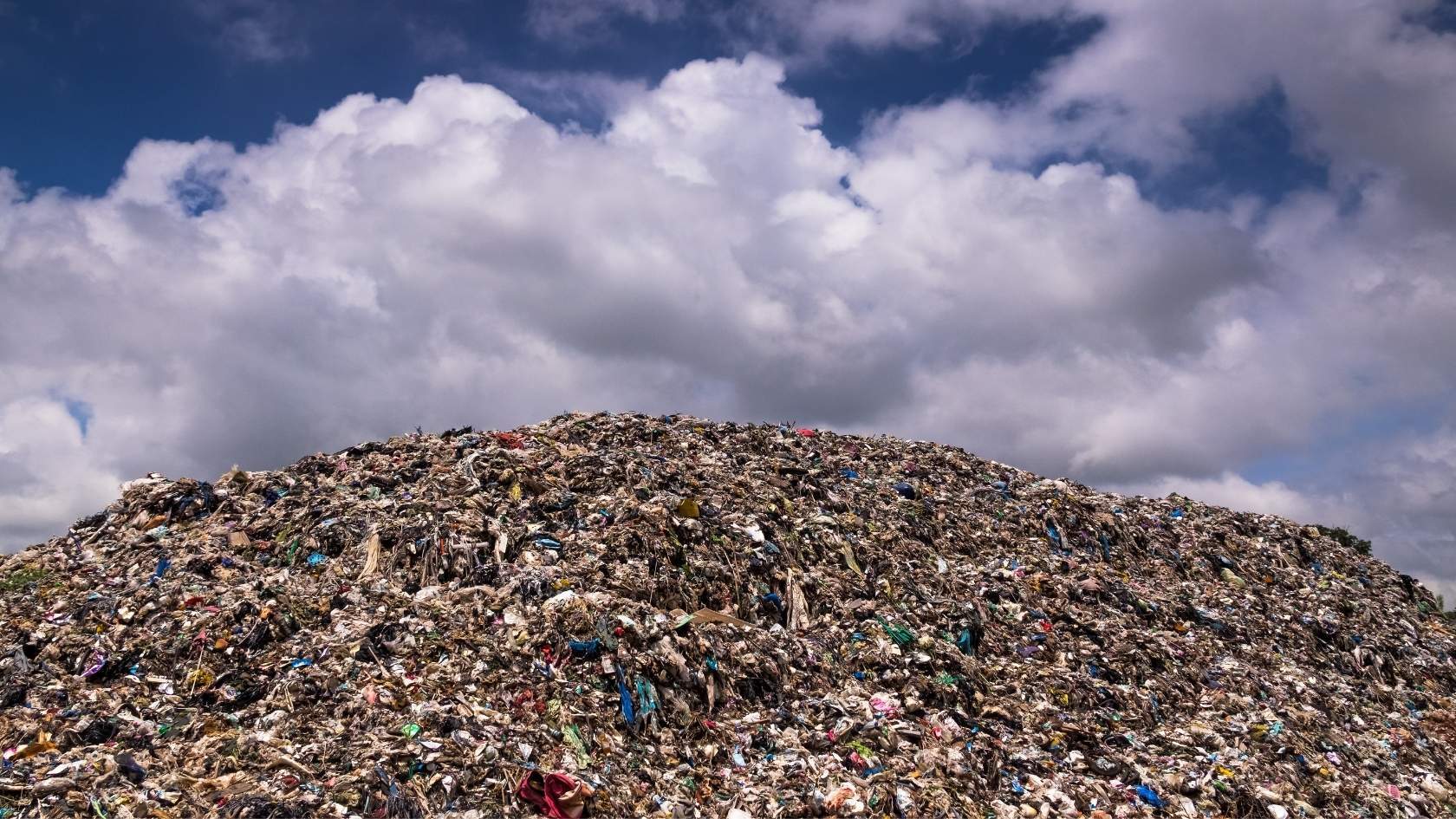Large landfill waste pile under cloudy sky